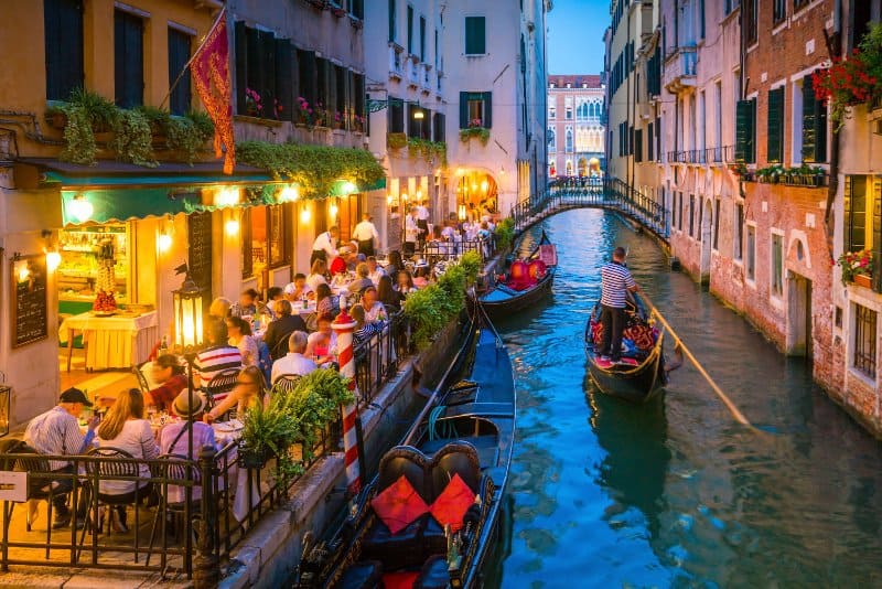 People having dinner next to a canal in Italy