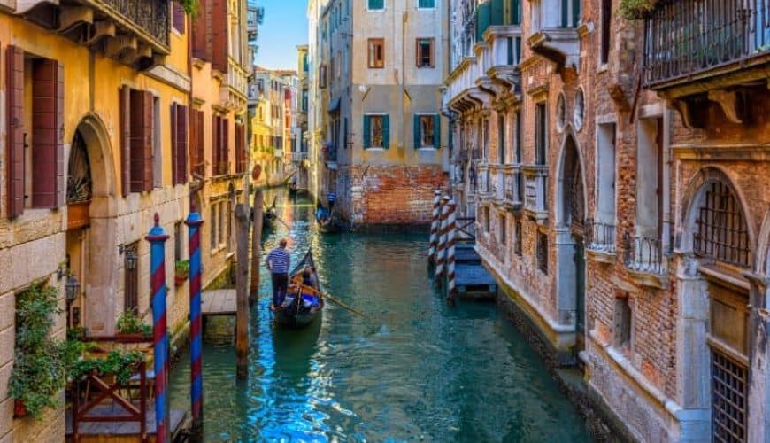 Narrow canal with gondola and bridge in Venice
