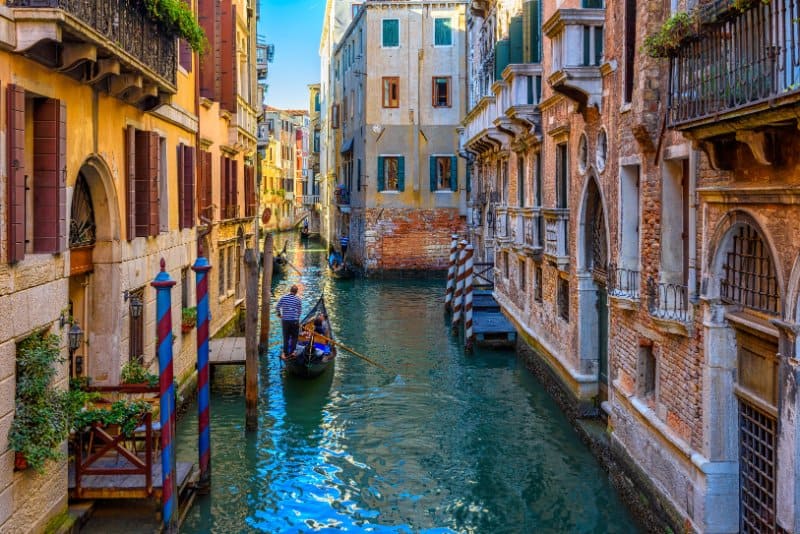 Narrow canal with gondola and bridge in Venice