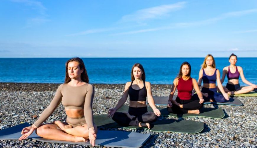 Five women doing morning yoga at the beach