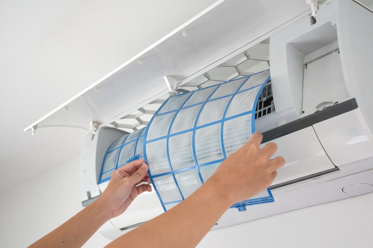 Hand installing a newly cleaned air conditioner filter