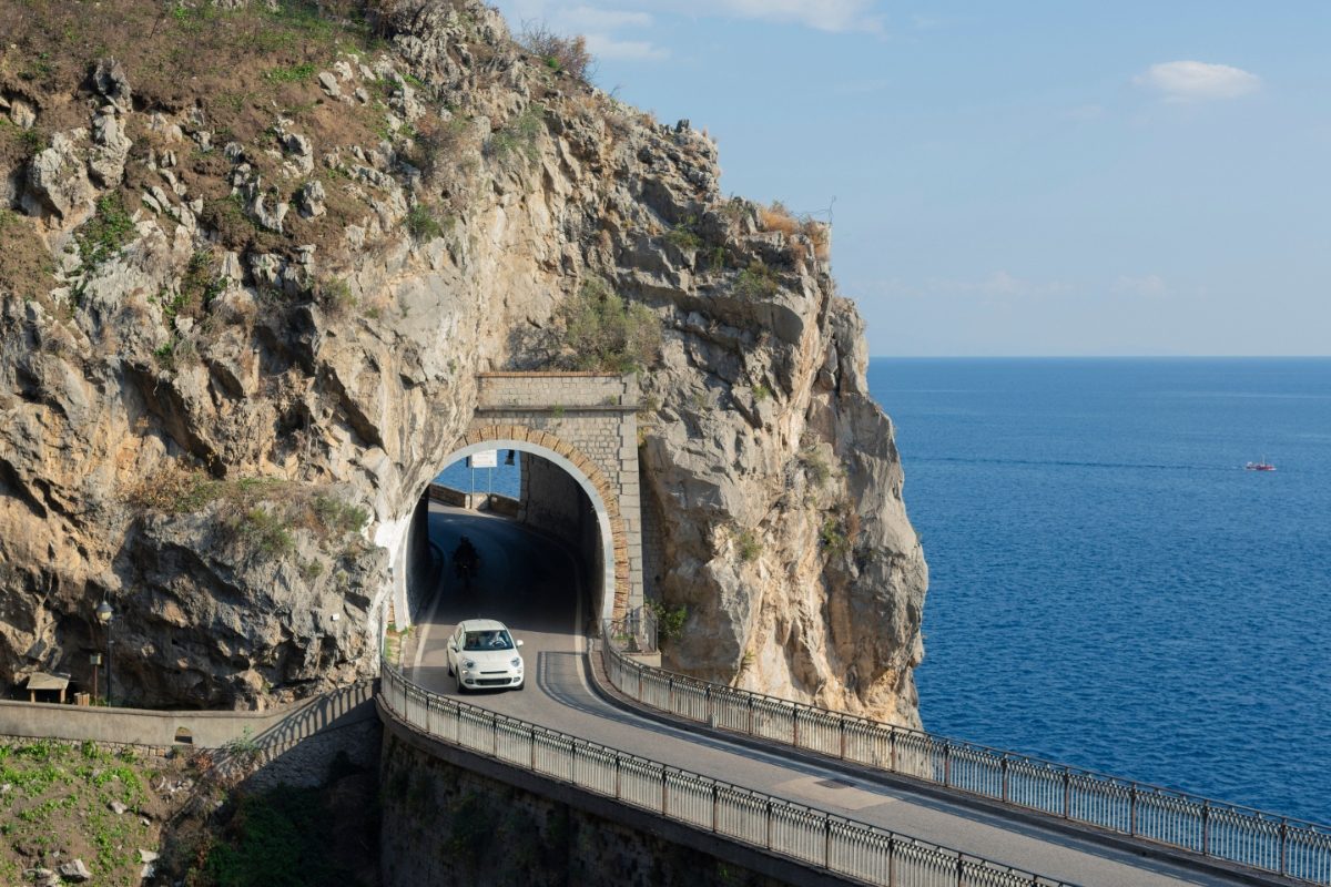 Small white car driving through the tunnel on Amalfi Coast road