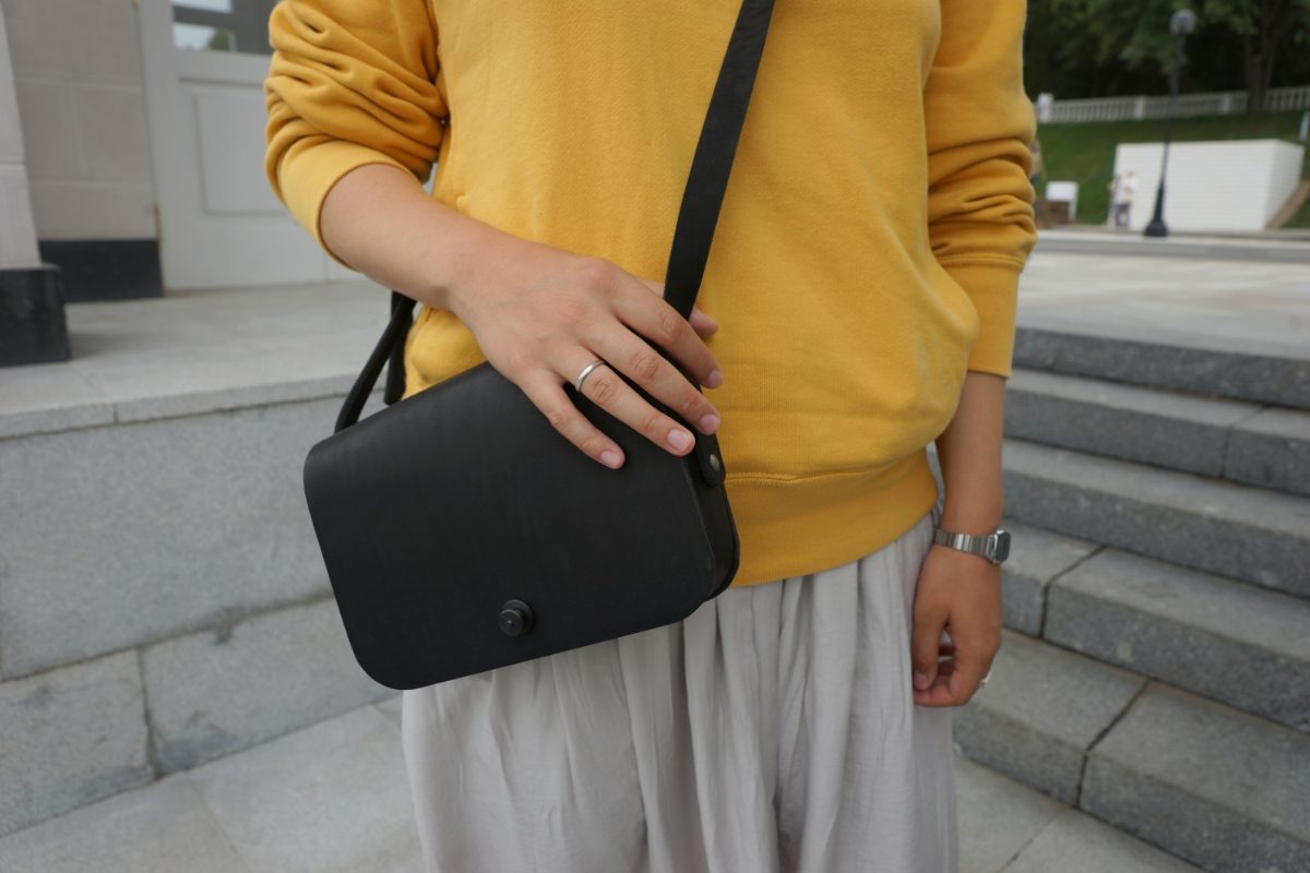 Woman wearing a yellow sweatshirt and a black stylish crossbody bag