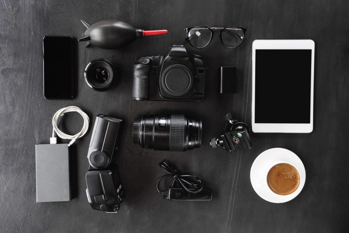 Top view of a camera and tech gear, including a phone and power bank, neatly arranged on a dark background