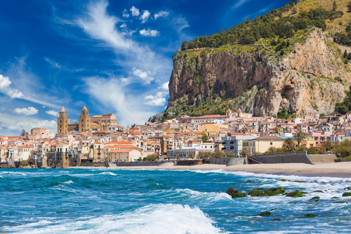 Panoramic view of the Cefalu resort town and ocean waves on Tyrrhenian coast on Sicily, Italy