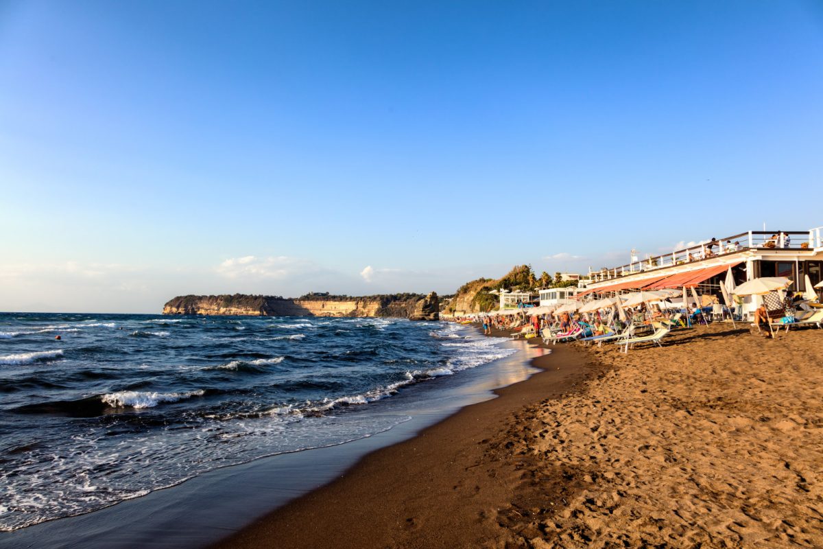 Lounges with umbrellas and the ocean view at Chiaiolella beach in Procida, Campania region, Italy