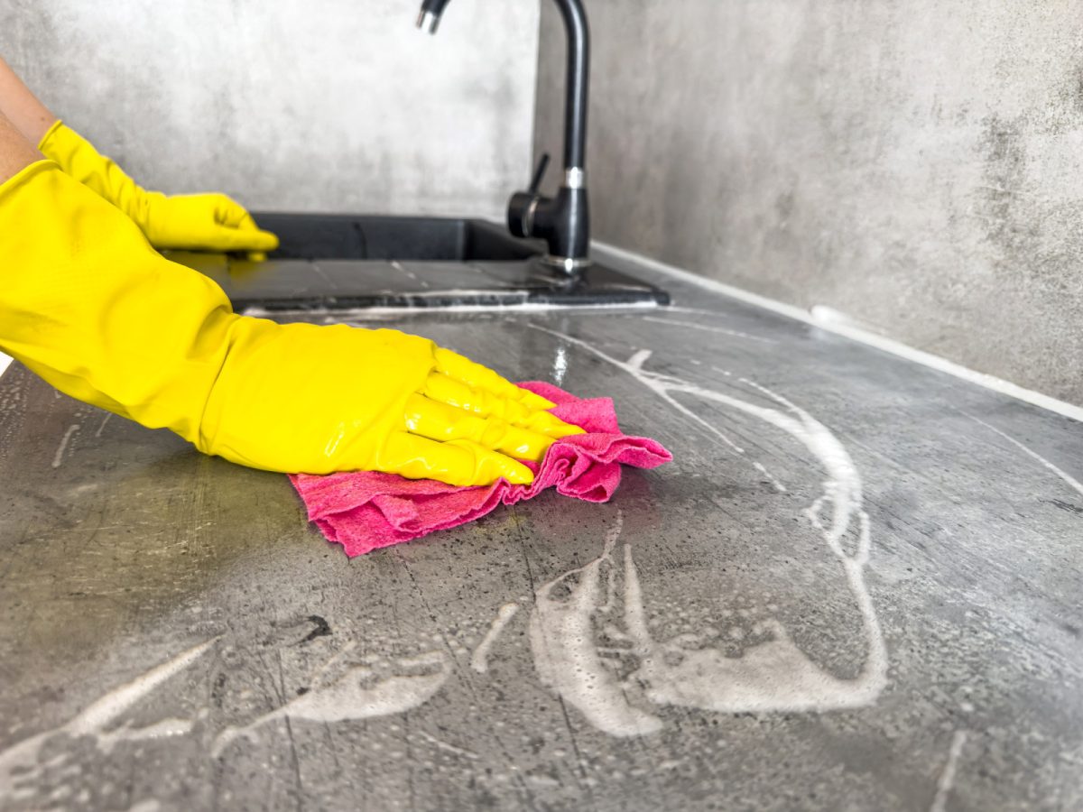 Cleaning and wiping down the cleaning countertop wearing a yellow rubber gloves