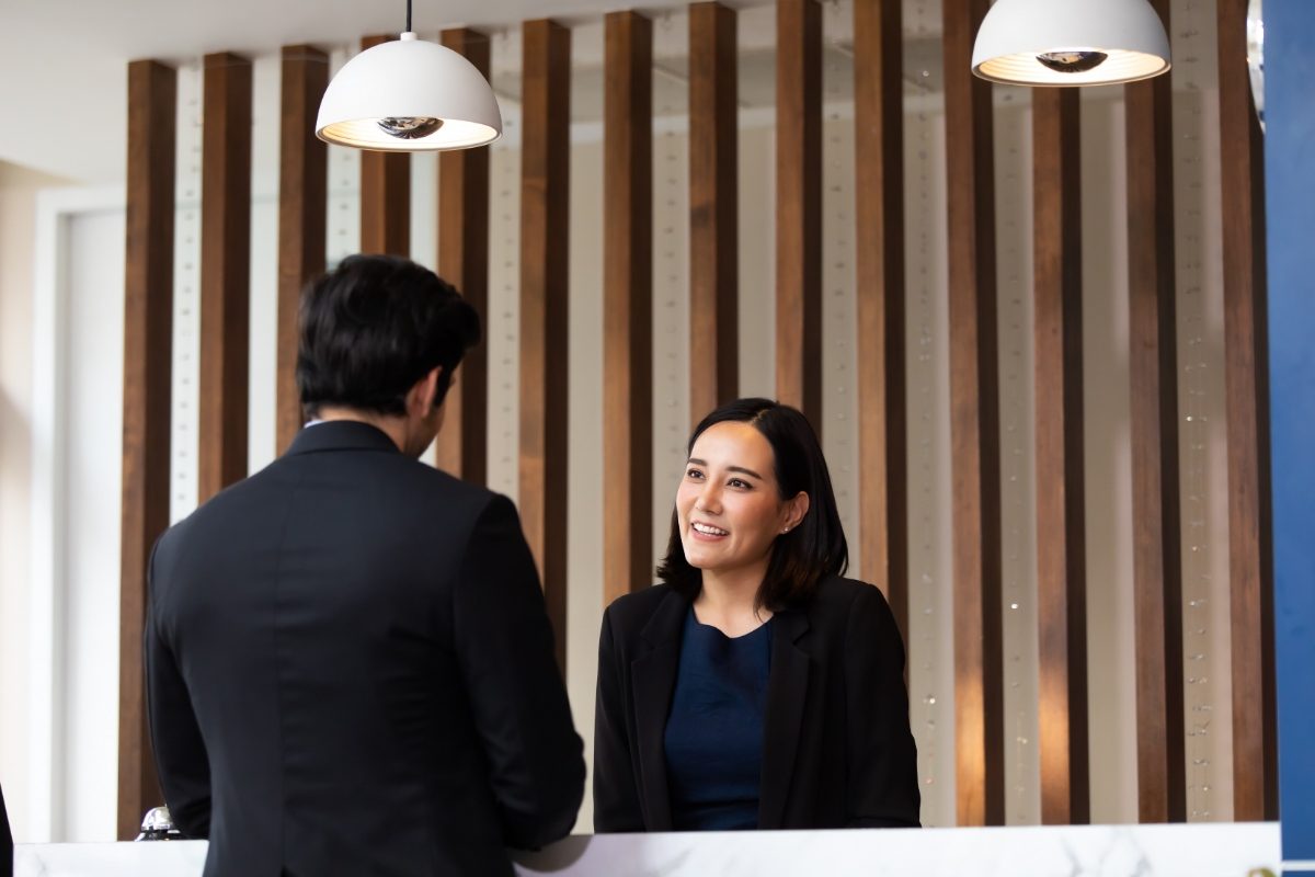 Man talking to a friendly female concierge and receptionist