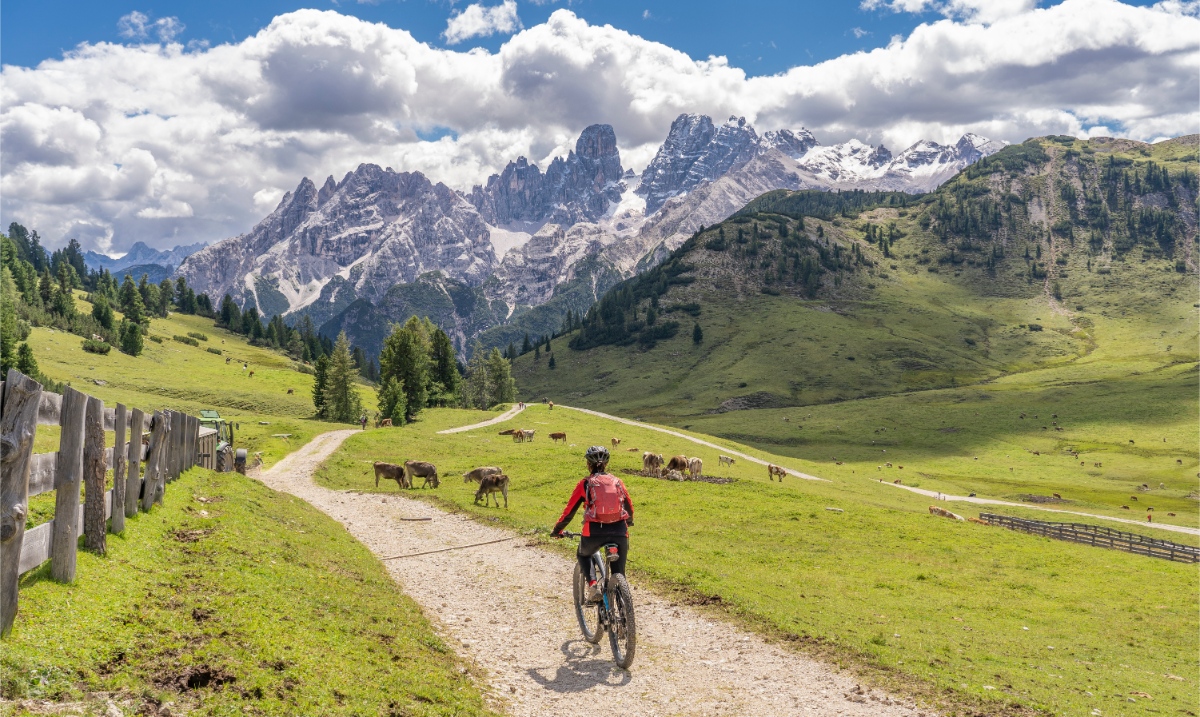 Woman riding a mountain bike cycling across the Pratto Piazzo in Dolomites, Italy