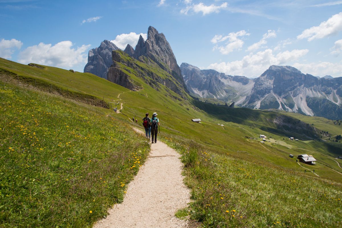 Group of hikers trekking a trail at the Sommer auf der Seceda in Dolomites, Italy