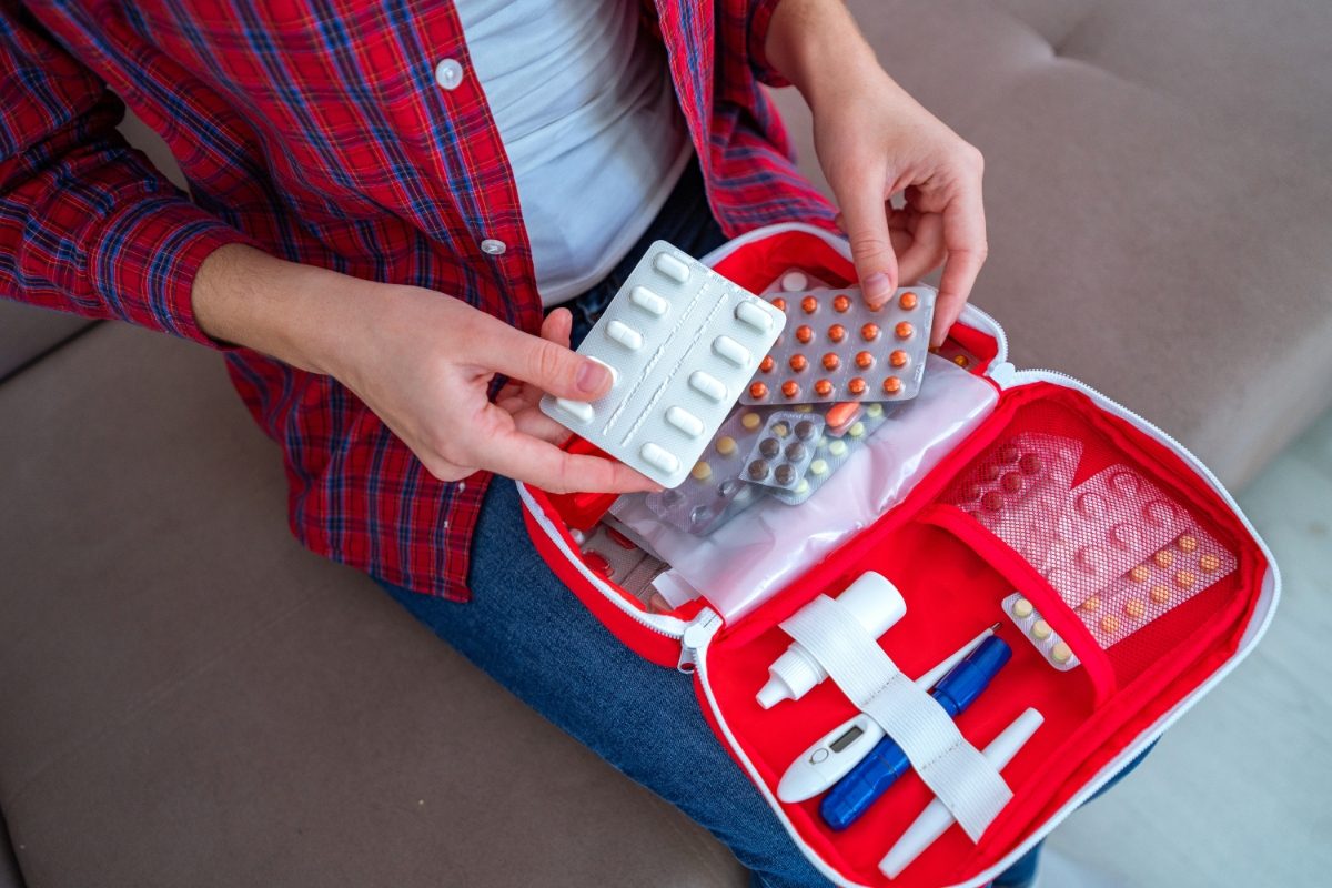 Woman with a first aid kit holding a medicine and pills