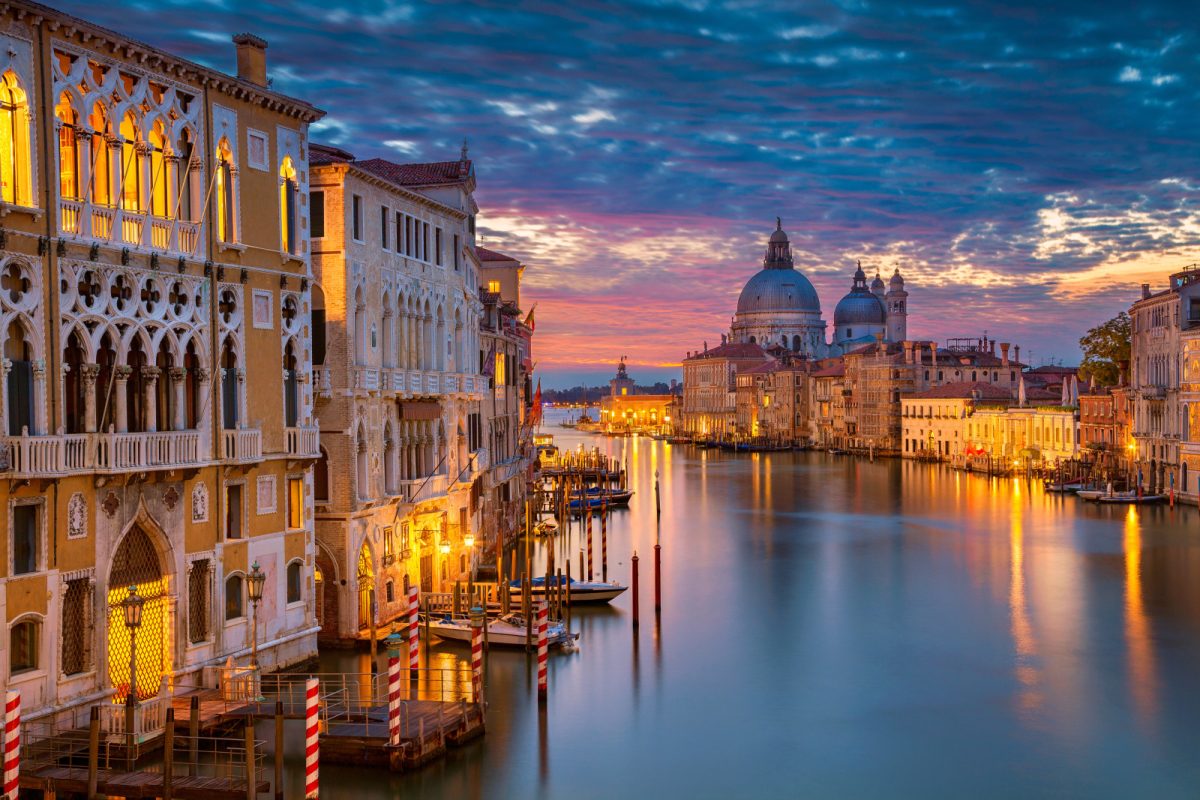 Panoramic view of Venice's Grand Canal at night, with the Basilica of Santa Maria della Salute as a stunning backdrop