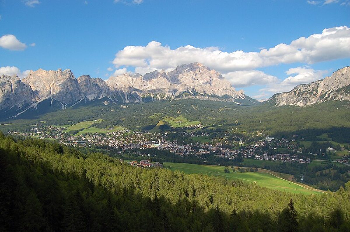 A scenic view of Italy in summer, with lush green mountains rising in the distance against a bright blue sky.