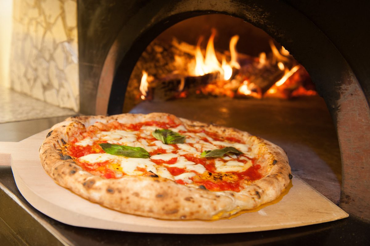 Taking Margherita Pizza or the Neapolitan Italian pizza out of the oven