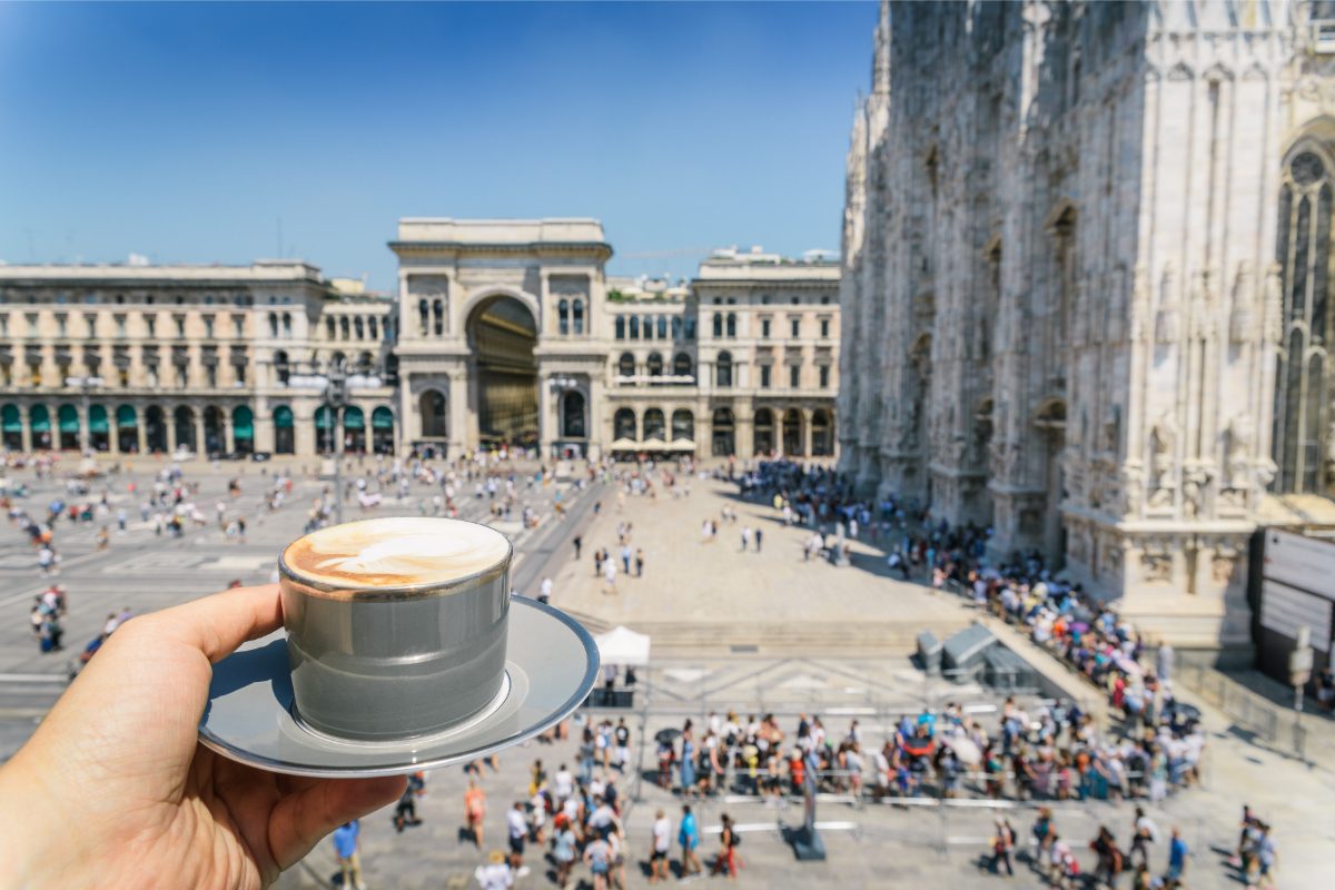 Holding a cup of cappuccino with a view of the Galleria Vittorio Emanuele II in the background, in Milan, Italy