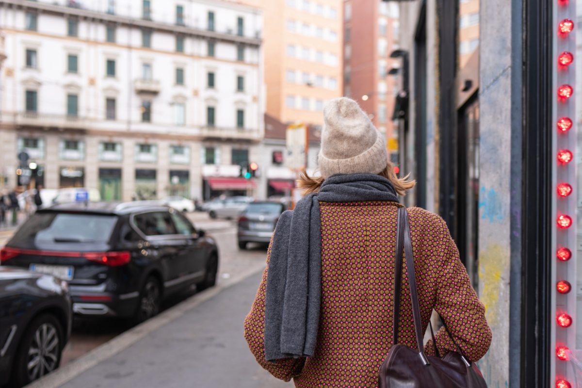 Female tourist in Milan wears a stylish cap and scarf, exuding a fashionable and chic vibe as she explores the city