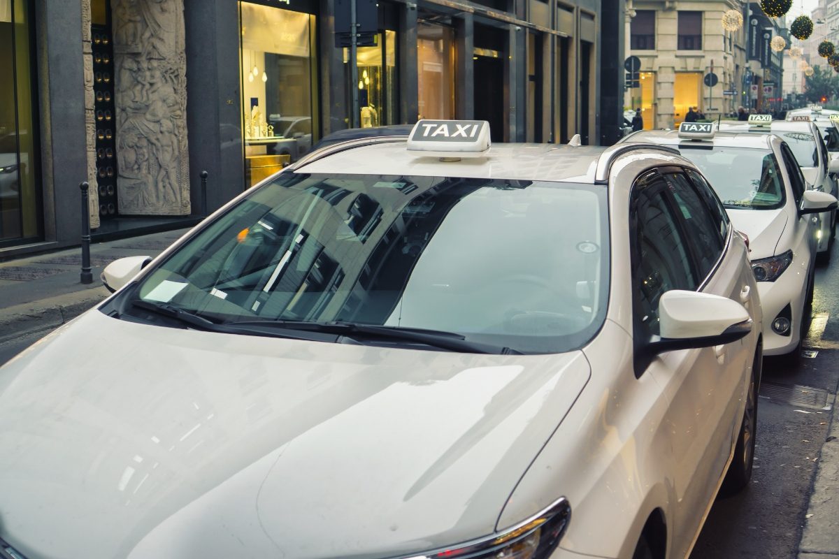 White taxi parked on a street in Milan, Italy