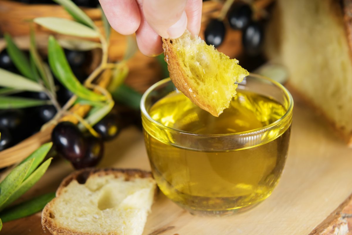 Dipping bread on a bowl of olive oil