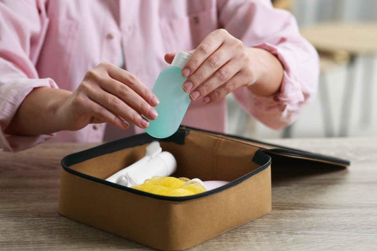 Woman packing a toiletry and cosmetic travel kit