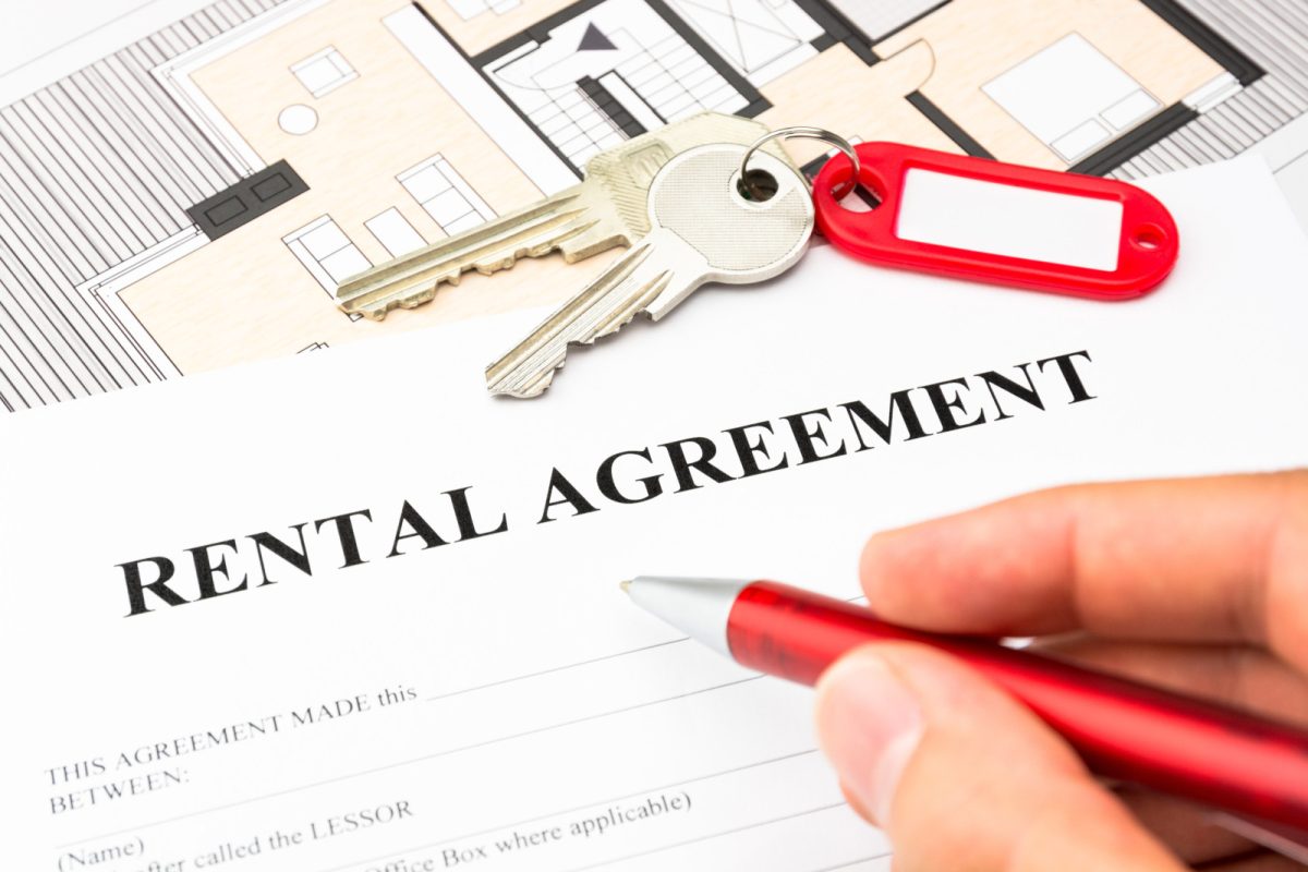 Signing a rental agreement form with tow keys on top