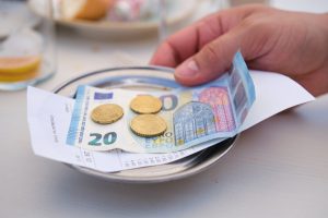 Hand holding a metal bill tray with a tip