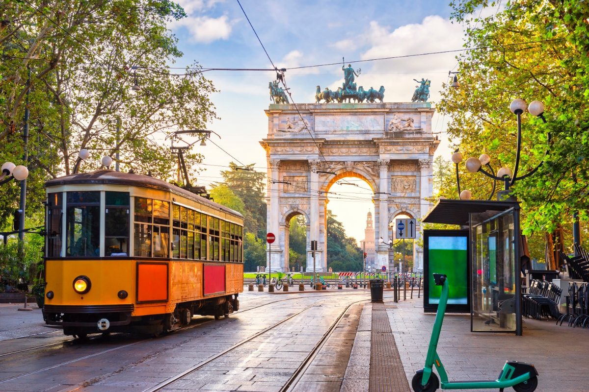 Vintage tram running in the streets next to the historic arch of Milan, Italy