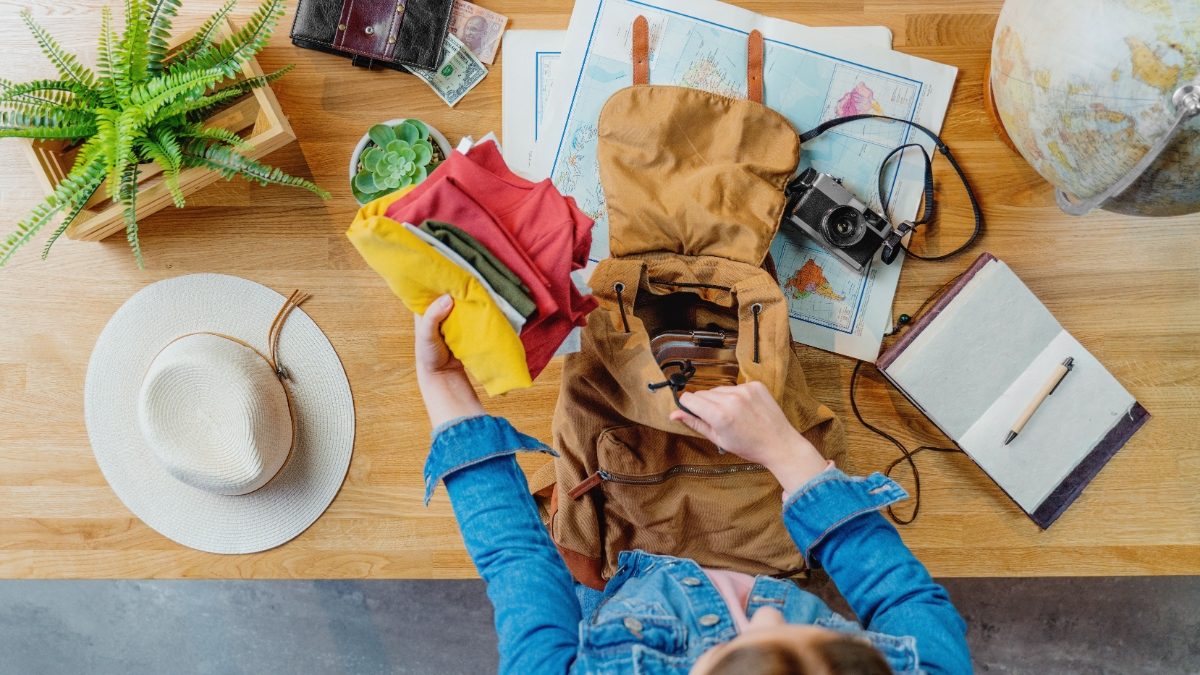 Top view of young woman packing a backpack for a vacation