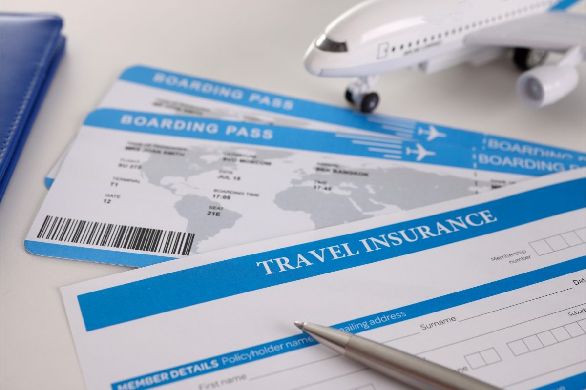 Close-up of a travel insurance application form, boarding pass, and a pen