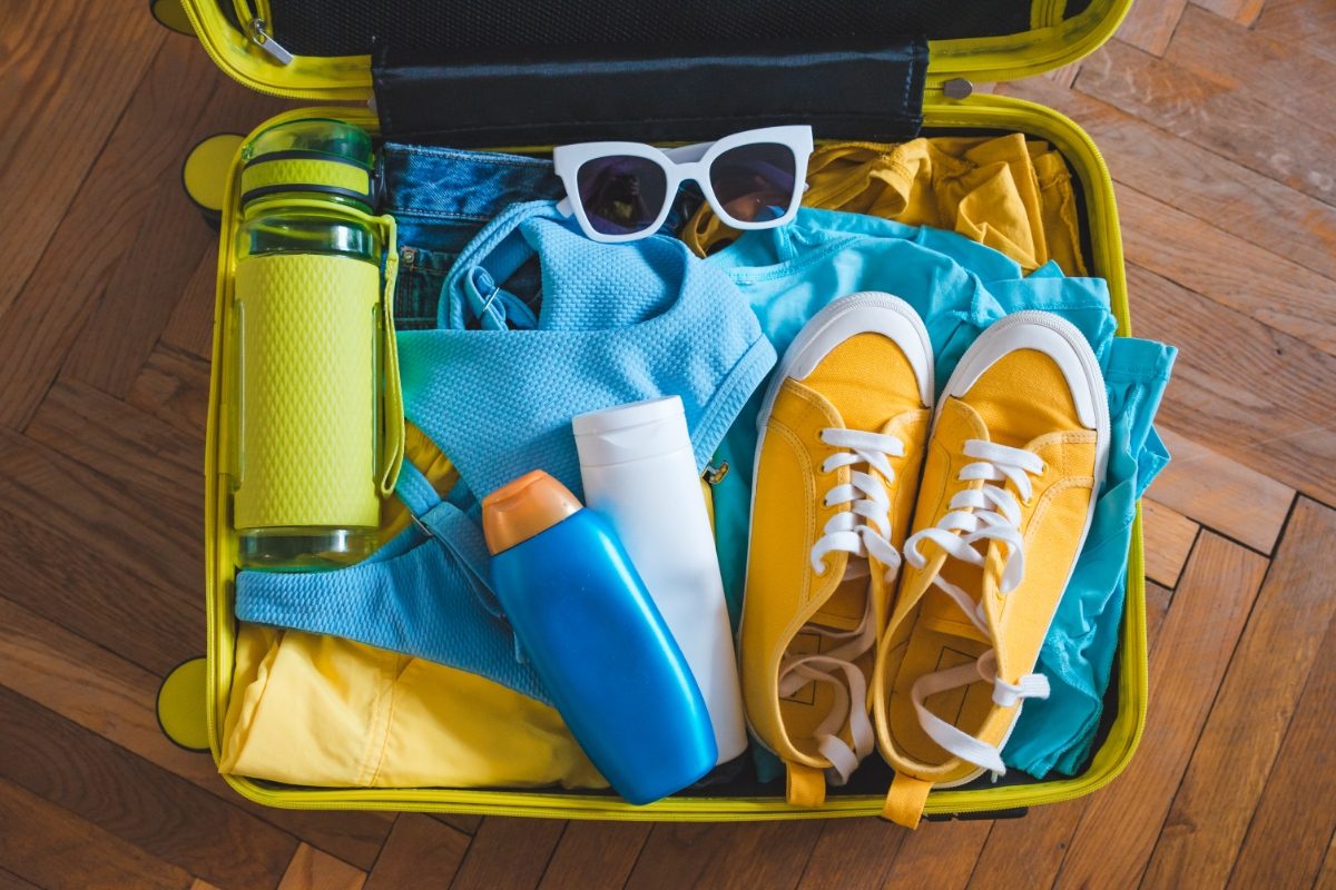 Open yellow luggage filled with clothes for travel packing