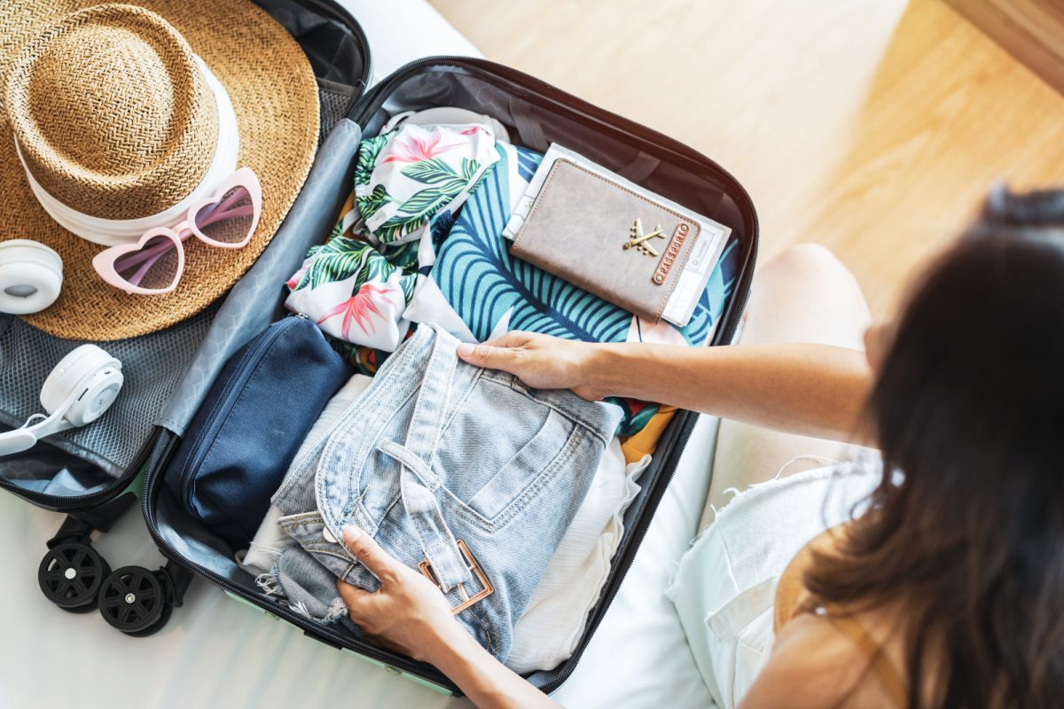 Young woman busy packing clothes and travel essentials into a suitcase, preparing for travel