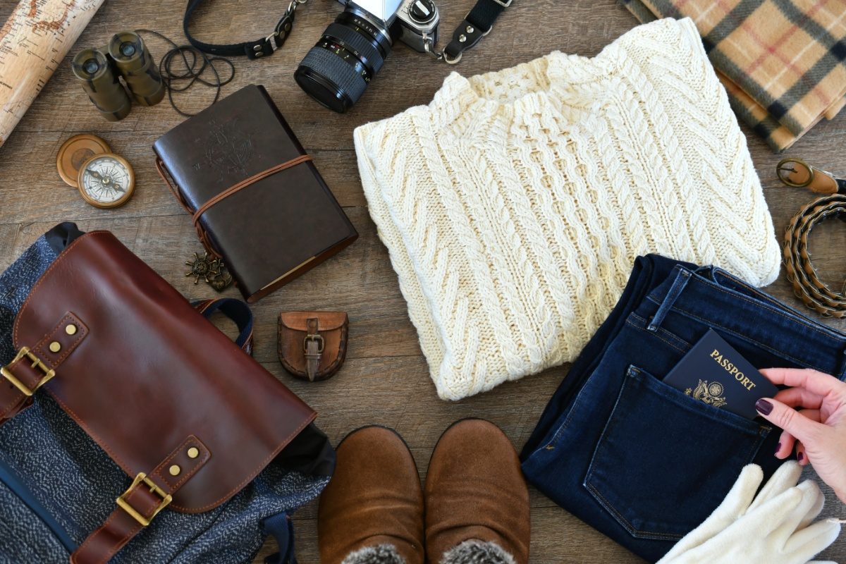 Winter clothes and accessories are laid out on the floor, neatly arranged and ready to be packed for a trip