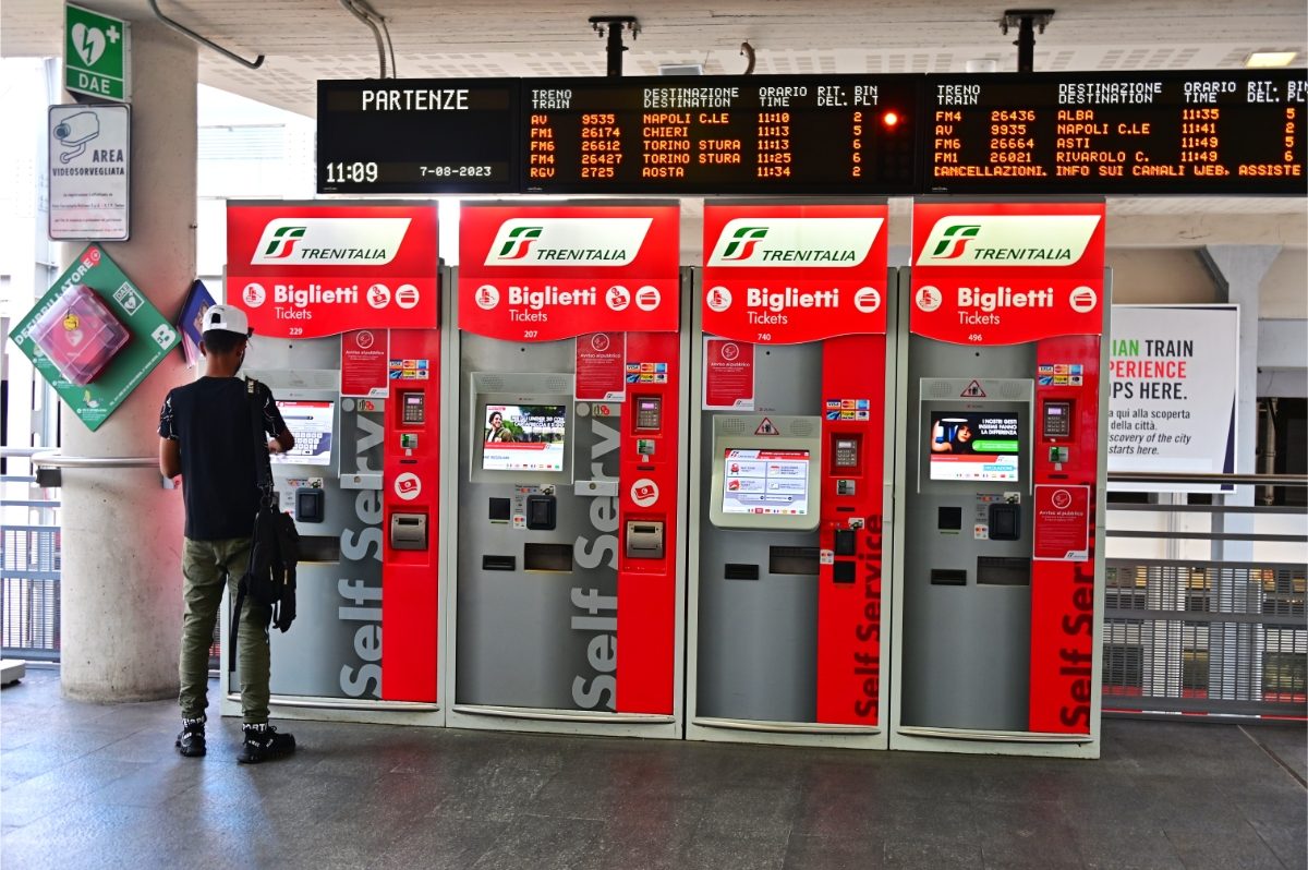 Man buying ticket from a Trenitalia train ticket machine in Turin, Italy