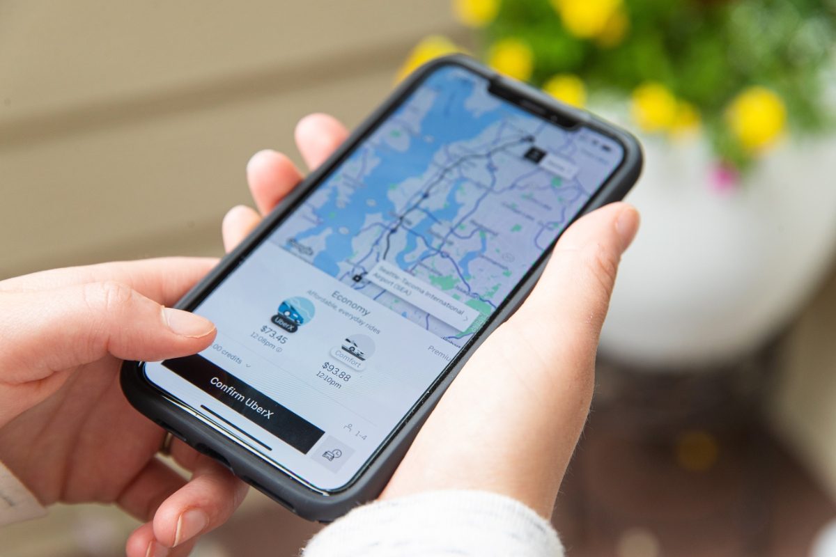 Hand holding a phone booking a ride on a Uber app