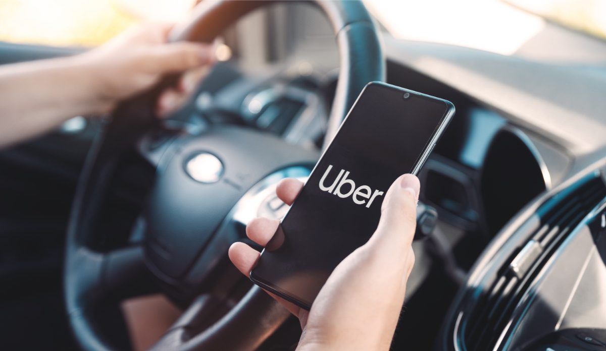 Driver using a phone displaying the Uber ride-sharing app