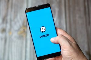 Hand holding a phone with the Waze app logo shown on the screen