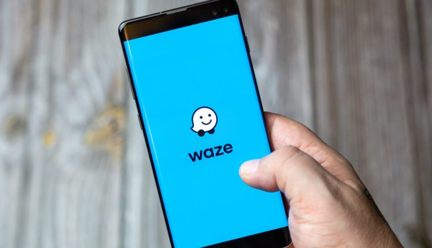 Hand holding a phone with the Waze app logo shown on the screen