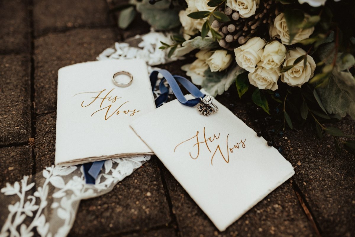 Close-up of wedding elopement rings, vows, and a bouquet