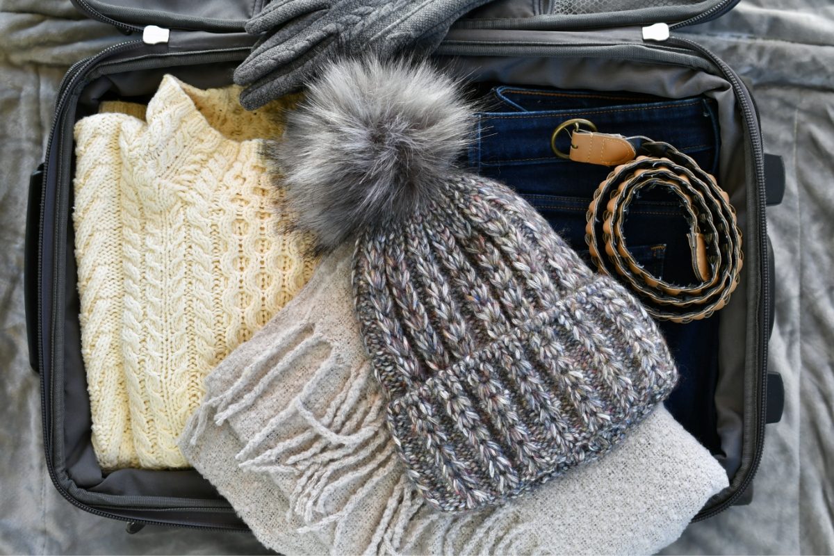 Open suitcase filled with winter clothes and accessories for travel