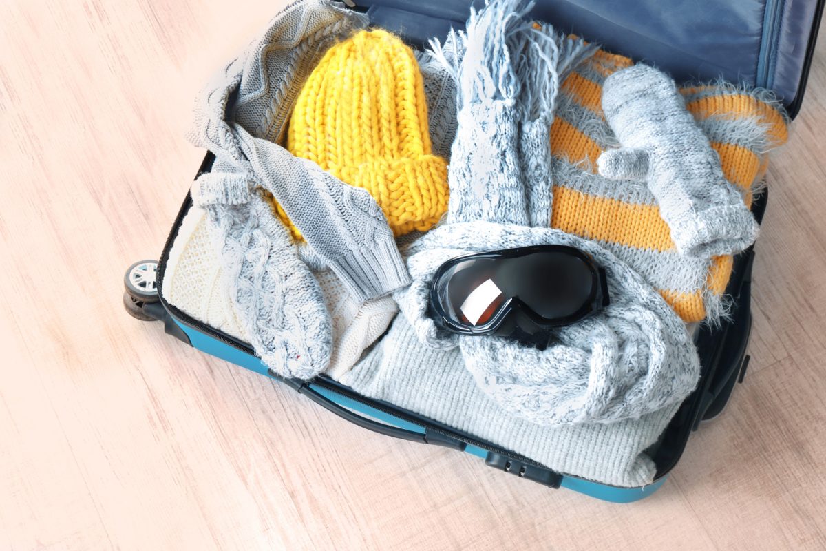 Open suitcase packed with winter clothes for a winter travel