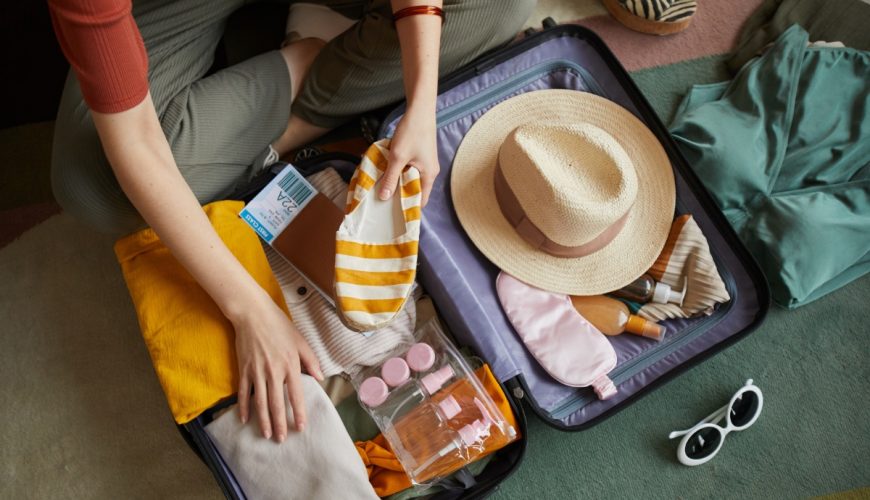 Top view of a woman gently packing clothes to a suitcase for vacation