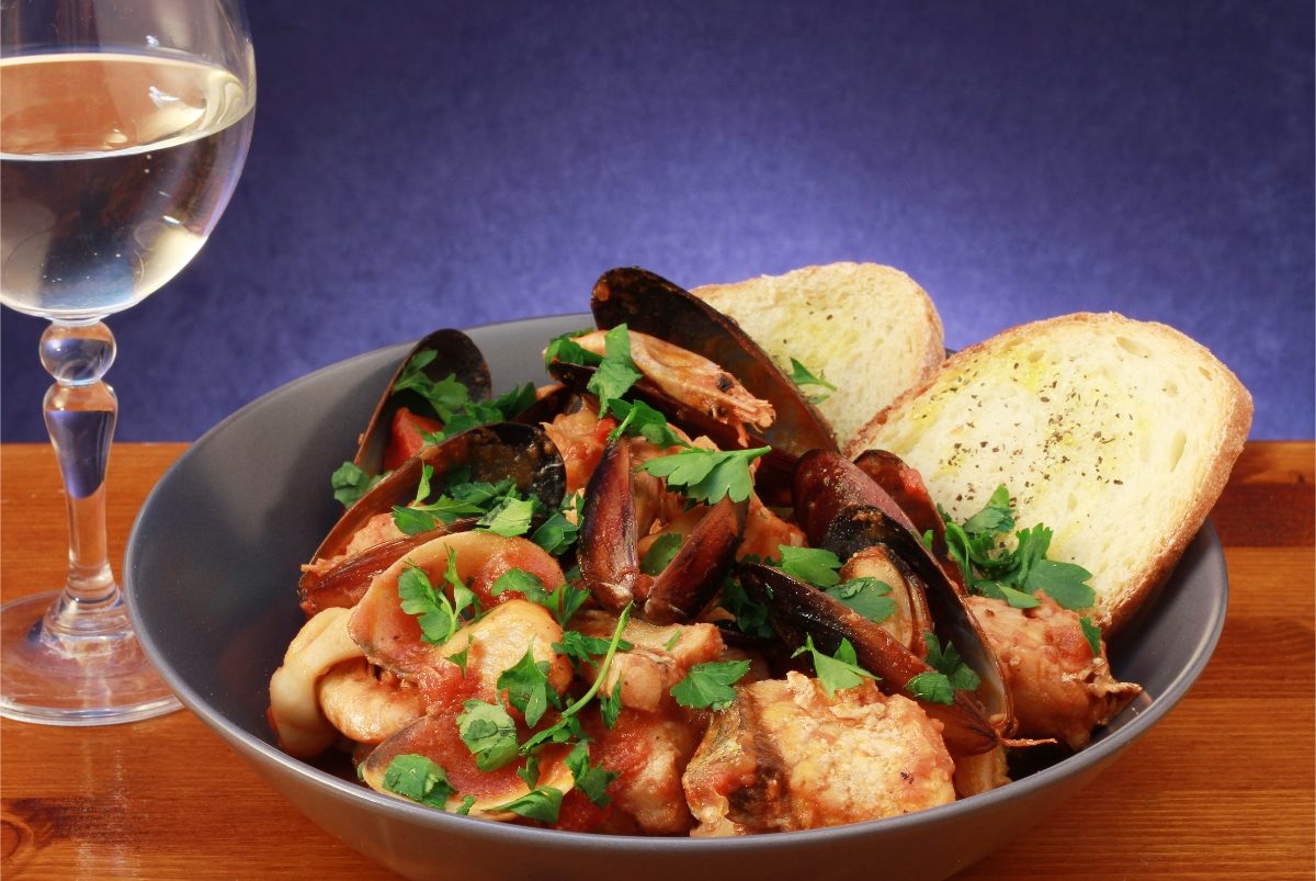 Zuppa di Pesce Italian fish stew served on a bowl next to a glass of wine